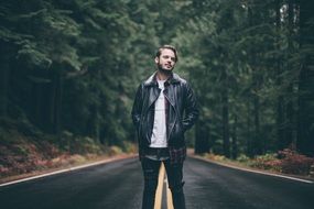 young man on the road among a pine forest