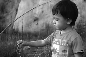 monochrome portrait of Child boy touching flower