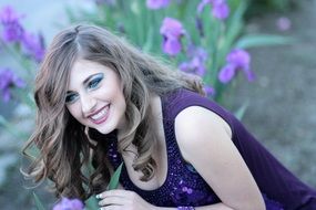 beautiful caucasian Girl in purple dress posing at iris flowers