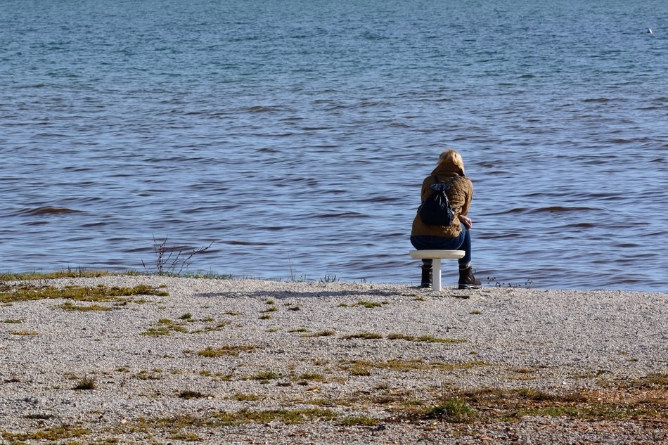 Person is sitting on the chair near the lake