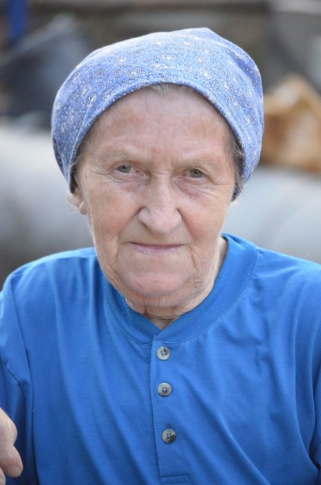 elderly woman farmer in blue clothes