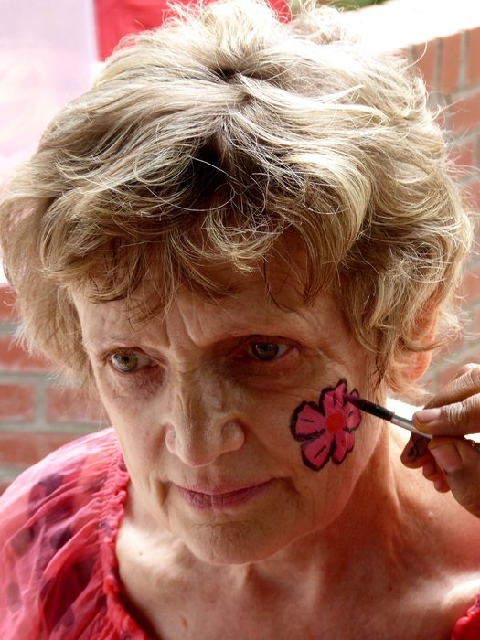 old woman with a bright flower on her cheek