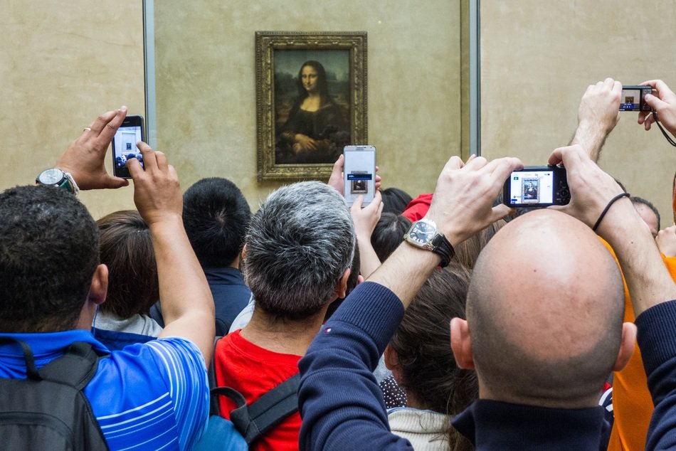 tourists near the portrait of mona lisa in the louvre museum