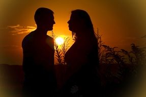 Silhouettes of the couple in love on golden sunset background