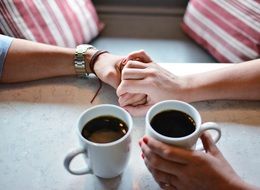 hands of lovers and two cups of coffee in an Italian cafe