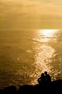 landscape of A romantic couple sit on the beach at sunset