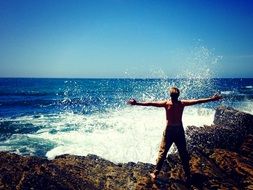 a man stands on a stone near the sea