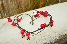 decorative heart with red berries on snow