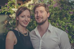 portrait of a couple in love near a green bush at dusk