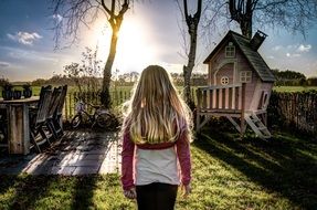 little girl stands in the sunlight in a playground