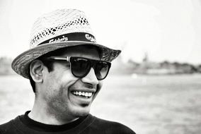 Smiling man in hat and glasses at sea, Black And White