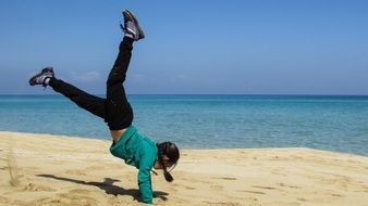 girl standing on arms with legs raised on the beach