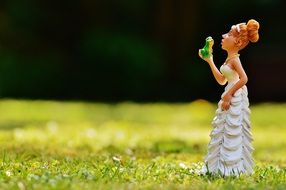 figure of the bride kissing the frog on green grass