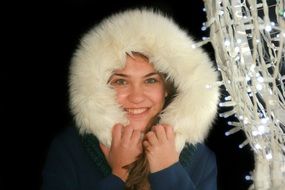 smiling beautiful girl in the hood near the festive garland