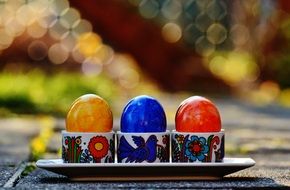 three colorful easter eggs in a stand