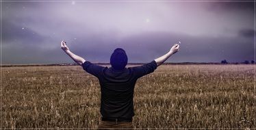 young man with arms wide open on a grain field