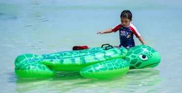 child with an inflatable turtle on the water