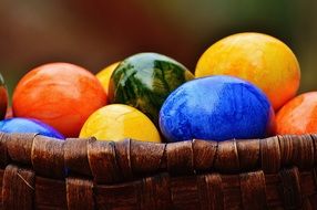 Closeup picture of bright multi-colored eggs in a basket