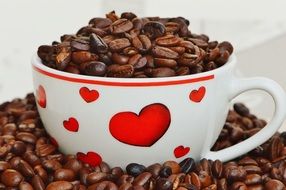 coffee beans in a white cup with red hearts