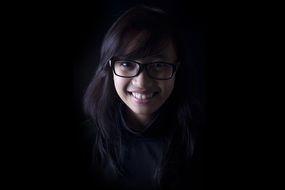 pretty dark haired Girl in eyeglasses, portrait on black background