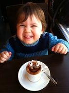 photo of a smiling child and a cup of hot chocolate in a cafe