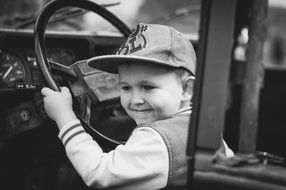 black and white photo of a child driving a car