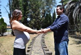 pregnant girl and her husband stand holding hands