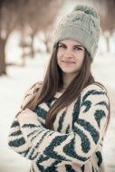 girl in a striped sweater and knitted hat on a background of a winter landscape