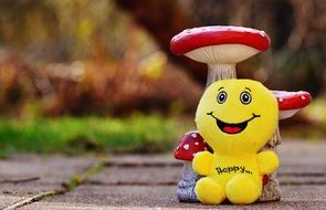 yellow soft emoticon near mushroom statuette