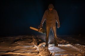 scary man with chainsaw on the path