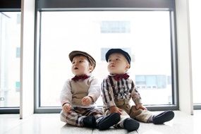 two little twins in festive attire against the window