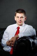 young man in a red tie in a chair