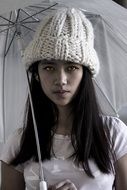 photo portrait of a girl in a knitted hat with a white umbrella