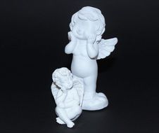 white figures of two angels on a black background