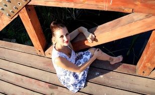 blonde sitting on the wooden bridge