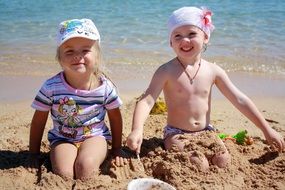 little girls in the sand near the water on a sunny day