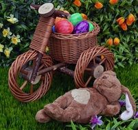 plush hare and wicker bike on green grass