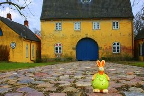Easter Bunny toy on pavement at colorful old house