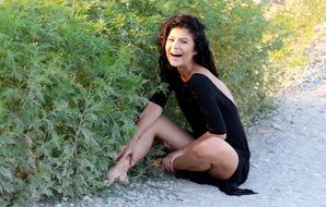 girl in a black dress sitting on the side of the road