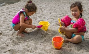 happy girls playing with sand on the beach
