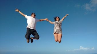 photo of a jumping couple against a blue sky