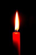red burning candle on a black background