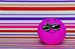 pink smiley with glasses on the background of multi-colored stripes