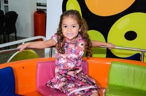 girl is sitting on a multi-colored sofa