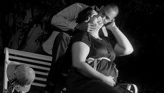 black and white photo husband kisses pregnant wife