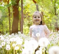 little girl among white dandelions