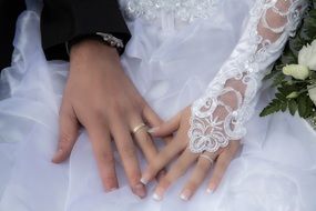 hands of the newlyweds on bridal dress