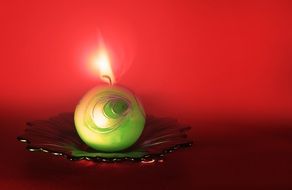 green candle burning at red background