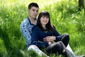 happy romantic couple sitting on grass