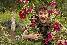 happy young man in burgundy flowers in the garden